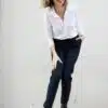 pantalon porté par une femme penchée vers l'avant, genoux pliés, chemisier blanc col ouvert porté manche 3/4 d'un côté, manche longue de l'autre